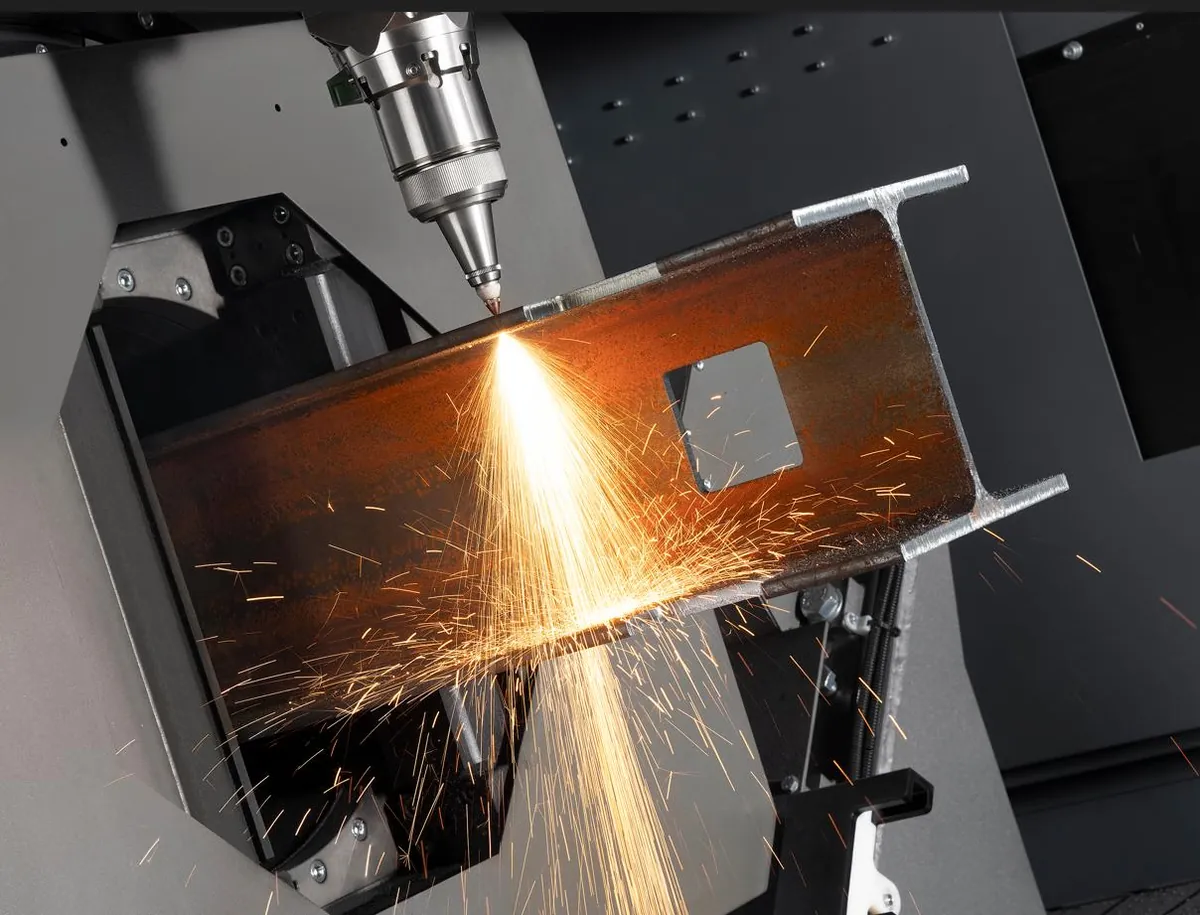 Tête laser découpant une poutrelle métallique, gerbe d'étincelles